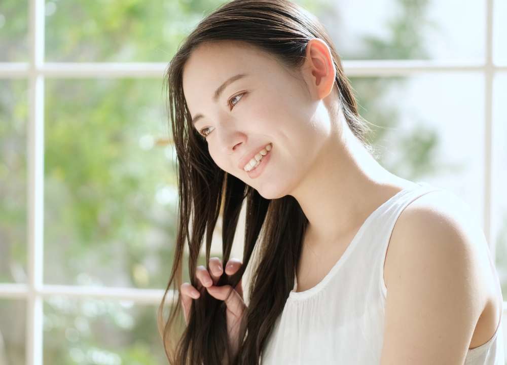 髪の毛に手をすべらす女性